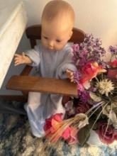 Doll, floral arrangement and doll bed.