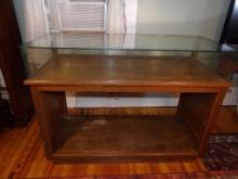DISPLAY CASE. WOODEN WITH GLASS TOP. SLIDING GLASS DOORS IN THE BACK. APPROX 48 X 21 X 36"