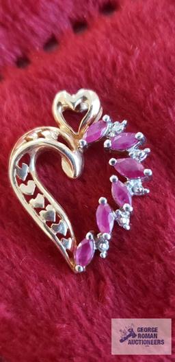 Gold colored heart-shaped pendant with red gemstones and clear gemstone chips, marked 10K,