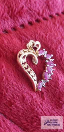 Gold colored heart-shaped pendant with red gemstones and clear gemstone chips, marked 10K,