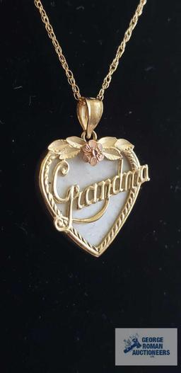 Gold colored Grandma pendant with pink flower and iridescent stone background, marked 14K on gold