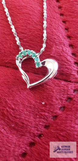 Silver colored heart-shaped pendant with green gemstones, marked 925, on silver colored twist