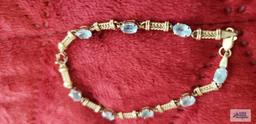 Gold colored bracelet with pale blue gemstones, missing one gemstone, marked 10K, approximate total