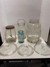 Glass butter churn, two other large glass jars, Blue jar and three glass pot lids