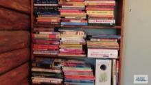 Three shelves of various books including recipe books, children's books, folk art magazine books,