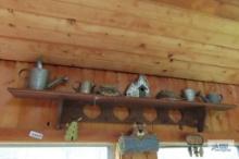 Lot of decorative watering cans, bear welcome sign and birdhouse